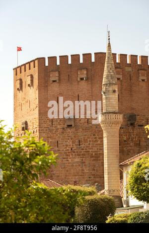 Alanya, Türkei. 7. April 2021 Minerett der Haci Kadiroglu Moschee vor dem berühmten Roten Turm im Hafen von Alanya, Südtürkei. Stockfoto