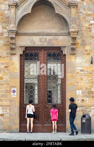 Touristen Familie Peeking in durch Kirche Doppeltüren in Florenz, Italien Stockfoto