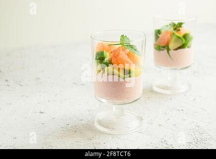 Zwei Gläser mit Vorspeise aus Tarama oder Taramosalata mit Avocado Und rosa Grapefruit auf dem hellgrauen Hintergrund Nahaufnahme mit Speicherplatz kopieren Stockfoto