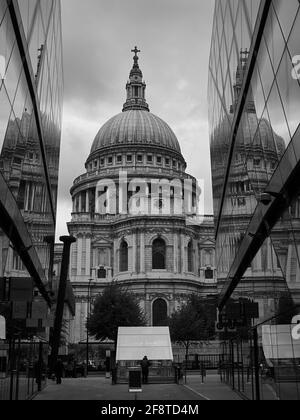 Die St. Paul's Cathedral spiegelt sich an den Glasseiten der umliegenden Gebäude. Eine im Vordergrund silhouettierte Person gibt ein Gefühl von Größe. Stockfoto