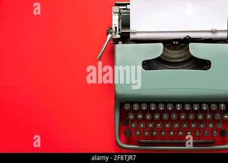 Vintage Schreibmaschine mit weißem Papier isoliert mit Kopierplatz auf Ein roter Hintergrund Stockfoto