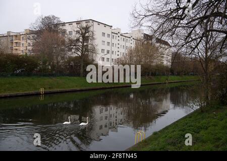 Berlin, Deutschland. April 2021. Wohngebäude spiegeln sich im Schifffahrtskanal Neukölln wider. Das Bundesverfassungsgericht hat die Mieterobergrenze, die 2020 in zwei Stufen in Kraft getreten ist, in einer am Donnerstag veröffentlichten Entscheidung für nichtig erklärt. Quelle: Paul Zinken/dpa-Zentralbild/dpa/Alamy Live News Stockfoto