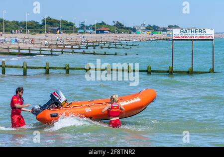 RNLI-Rettungsschwimmer bereiten eine Rippe vor, um an einem Sommertag an der britischen Küste in Littlehampton, West Sussex, England, zu einem Zwischenfall auf See zu eilen. Stockfoto