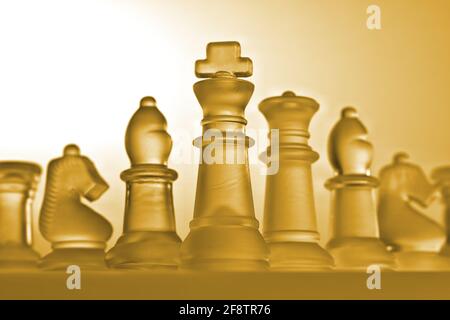 Deutschland. April 2021. Symbolische Schachfiguren eines Schachspiels aus Glas mit neutralem Hintergrund. Detail einiger weißer Figuren mit einer golden/gelben Lichtstimmung aus der Perspektive eines leichten Frosches. Credit: dpa/Alamy Live News Stockfoto