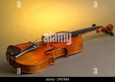 Deutschland. April 2021. Eine alte Geige mit leichten Kratzern und Beschädigungen liegt auf einem neutralen, grauen, gelb beleuchteten Hintergrund. Credit: dpa/Alamy Live News Stockfoto