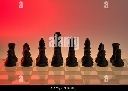 Deutschland. April 2021. Symbolische Schachfiguren eines Schachspiels aus Glas mit neutralem Hintergrund. Grundstellung der schwarzen Figuren mit roter Lichtstimmung und Reflexionen der Schachfiguren auf dem Glasschachbrett. Credit: dpa/Alamy Live News Stockfoto