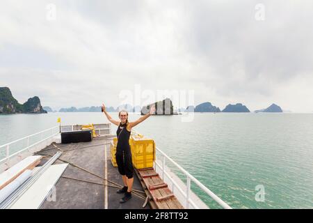 Wunderschöne Landschaft mit einer jungen lächelnden Frau aus der Bai TU Long Bay, die während der Kreuzfahrt zur Insel Quan Lan, Vietnam, aufgenommen wurde. Landschaftsfoto am Meer, aufgenommen im Süden Stockfoto
