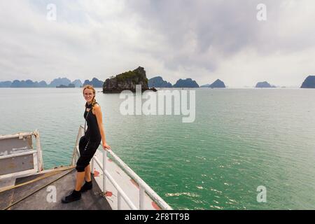 Wunderschöne Landschaft mit einer jungen lächelnden Frau aus der Bai TU Long Bay, die während der Kreuzfahrt zur Insel Quan Lan, Vietnam, aufgenommen wurde. Landschaftsfoto am Meer, aufgenommen im Süden Stockfoto