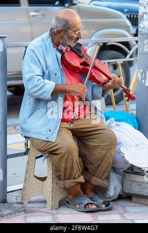 Der alte Jude spielt auf der Straße Geige. Sonniger Sommertag. Vorderansicht. Krim, Sudak - 10. Oktober 2020. Stockfoto