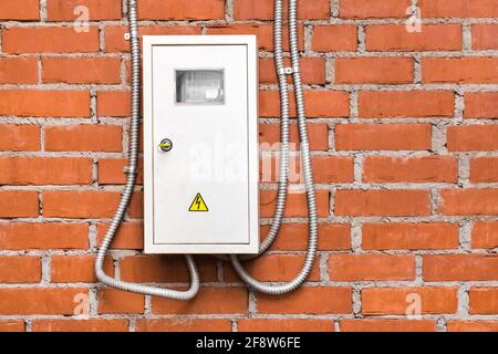 Schutz eines Stromzählers vor dem Hintergrund einer Ziegelwand einer Heizungsanlage bei einem Industrieunternehmen. Stockfoto