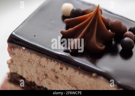 Der Kuchen ist dekorativ dekoriert. Französisches Gebäck mit Schokoladencreme. Teil der Kuchenplatte und Seitenansicht Nahaufnahme. Stockfoto