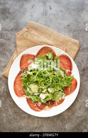 Typisches italienisches Gericht namens „Carpacio“ aus Brasaola-Fleisch (von der Kuh) Aragula und Parmesankäse Stockfoto