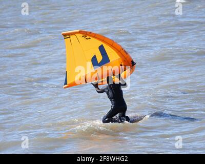 Sheerness, Kent, Großbritannien. April 2021. UK Wetter: Sonnig in Sheerness, Kent. Ein Mann versucht die neue Sportart der Tragflügeldrachen oder des "Flügelsurfens" oder "Flügelfolierung" - ein Hydrofoil-Board mit einem kleinen Drachen, den man direkt hält - anstatt die Kontrolle über mehrere Saiten und ein Geschirr wie beim traditionellen Kitesurfen zu haben. Kredit: James Bell/Alamy Live Nachrichten Stockfoto