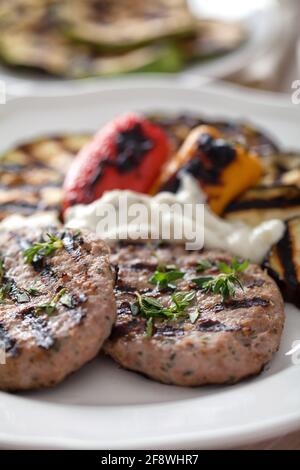 Hamburger mit gegrilltem gemischtem Gemüse auf einem Teller. Stockfoto