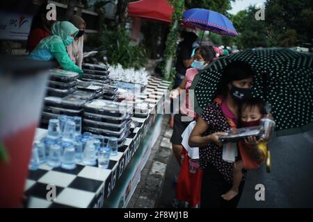 Jakarta, DKI Jakarta, Indonesien. April 2021. Die Bewohner stehen Schlange, indem sie die Entfernungsregel anwenden, um takjil am Donnerstag auf den Straßen von Zentral-Jakarta frei zu bekommen (04/15/2021). Die Bewohner müssen sich anstellen, indem sie einen Abstand von zwei Metern einlegen, um die Ausbreitung des Coronavirus zu verhindern. Jeden Tag stellt das Komitee 400-600 takjil-Pakete kostenlos zur Verfügung, die Spenden von Anwohnern und Unternehmen in der Region sind. Quelle: Muhammad Zaenuddin/ZUMA Wire/Alamy Live News Stockfoto