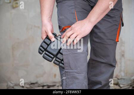 Nicht erkennbarer Baumeister, der Knieschützer trägt, um in einer Konstruktion zu arbeiten. Sicherheit am Arbeitsplatz. Stockfoto