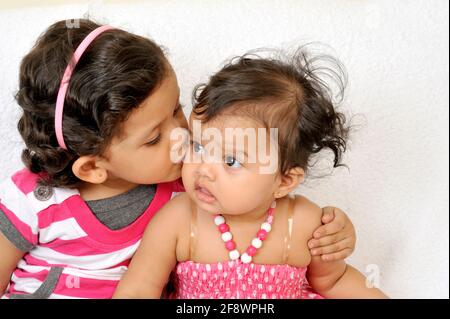 Mumbai, Maharashtra, Indien- Asien, 27. November; 2011- Indian Happy Family Four Years Elder Sister Kissing Three Months Cute Little Girl White Background Stockfoto