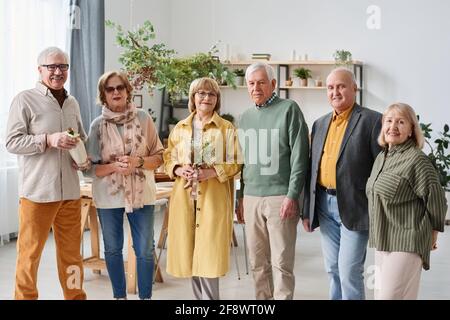 Gruppe von älteren Menschen in formeller Kleidung lächelt vor der Kamera Im Raum stehend Stockfoto