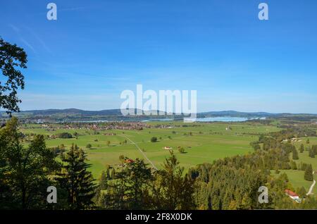 Blick vom Schloss Neuschwanstein auf die dahinterliegende flache Seenplatte Mit einem sonnigen, klaren blauen Himmel Stockfoto