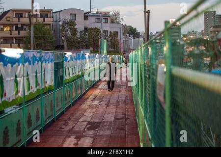 Ein älterer japanischer Salaryman mit schickem Business-Anzug, der bei Sonnenuntergang am Bausteg entlang läuft, Yamate Dori, Tokio, Japan Stockfoto