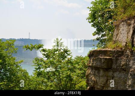 Blick von einem Felsen plato zwischen Felsen und Bäumen zu Die kanadischen Niagarafälle bei sonnigem Wetter Stockfoto