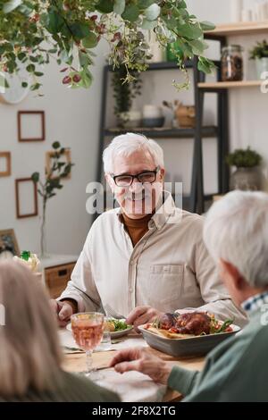 Glücklicher älterer Mann, der am Tisch saß und zu Abend gegessen hat Zusammen mit seinen Freunden zu Hause Stockfoto