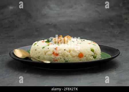 UPMA aus Samolina oder rava Upma, dem berühmtesten südindischen Frühstückselement, das wunderschön auf einem Teller mit Bananenblatt angeordnet und mit einem garnierten Blätterteller serviert wird Stockfoto