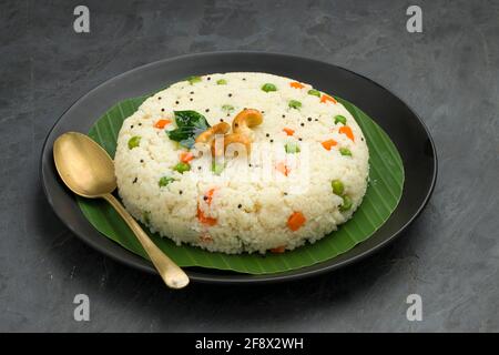 UPMA aus Samolina oder rava Upma, dem berühmtesten südindischen Frühstückselement, das wunderschön auf einem Teller mit Bananenblatt angeordnet und mit einem garnierten Blätterteller serviert wird Stockfoto