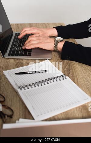 Beschnittene Ansicht einer Geschäftsfrau, die ein Notebook in der Nähe eines Notebooks verwendet, auf verschwommen Vordergrund auf Grau isoliert Stockfoto