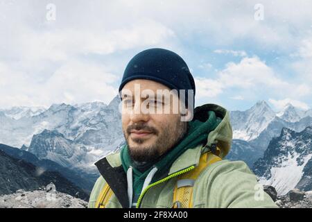 Mann mit Rucksack Trekking in den Bergen. Kaltes Wetter, Schnee auf Hügeln. Winterwanderporträt. Stockfoto