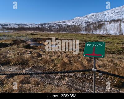 Schild Warnung vor der hohen Temperatur des heißen Wassers vor der dampfenden heißen Quelle in Geysir Geothermie Feld, Teil des Goldenen Kreises, im Winter. Stockfoto