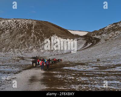 Menschen wandern zum kürzlich erupten Vulkan am Fagradalsfjall im Geldingadalir-Tal auf der Halbinsel Reykjanes, auf einem Pfad, der im Winter Berge hinaufklettert. Stockfoto