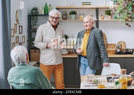 Gruppe älterer Männer, die Wein trinken und mit jedem sprechen Andere während des Abendessens zu Hause Stockfoto