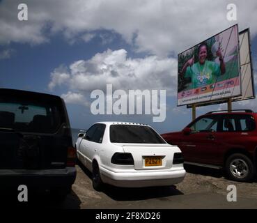 St George's Grenada Cars in Car Park by Billboard mit Blick auf Das Meer Stockfoto