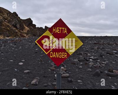 Nahaufnahme eines rot-gelben Schildes, das vor der starken Strömung am Strand von Djupalonssandur an der Küste der Halbinsel Snaefellsnes warnt. Stockfoto