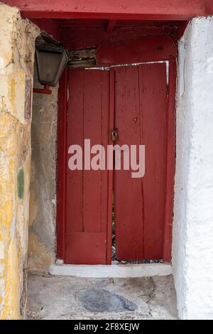 Rote Holztür, geschlossener und verschlossener Hauseingang. Traditionelle Gebäudefassade, Altstadt von Plaka, Athen, Griechenland Stockfoto