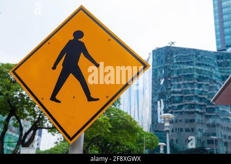 Gelbes Straßenschild mit Fußgängerüberwegen, das am Straßenrand angebracht ist In der Stadt Stockfoto