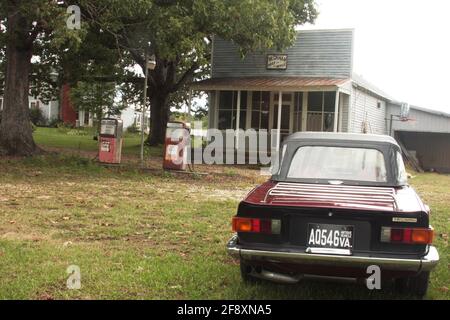 Appomattox County, VA, USA. Das alte Postamt von Beckham mit einer verlassenen Tankstelle im Vorgarten. Antikes Triumph-Fahrzeug. Stockfoto