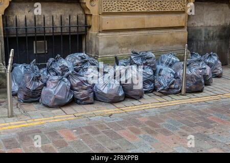 Müllsäcke warten darauf, auf einer Stadtstraße gesammelt zu werden, Glasgow, Schottland, Großbritannien Stockfoto