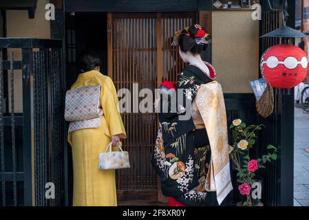 Japanische Geisha Maiko. Der Darsteller und der Begleiter, der an der Tür des Klienten anruft. In traditionellem Kimono-Kleid und weißem Make-up. Gion, Kyoto, Japan Stockfoto