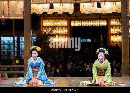 Geisha trägt Kimono, tanzt und tritt vor Publikum auf der Bühne auf. Schöne und elegante Maiko. Yasaka-Schrein, Kyoto, Japan. Stockfoto