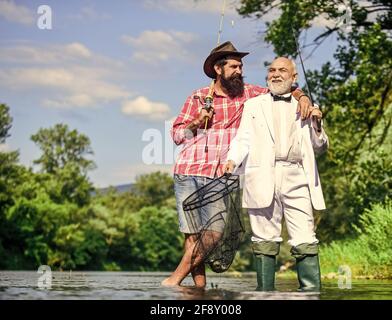 Angeln. Fliegenfischen Abenteuer. Rentner Vater und reifer Sohn mit Bart. Freunde Männer mit Angelrute und Netz. Glückliche Fischer im Wasser. Hobby Stockfoto