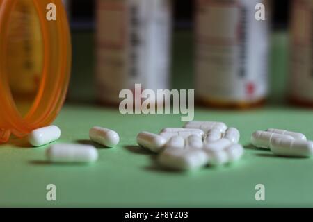 Selektiver Fokus auf Medikamentenflasche und weiße Pillen. Weiße Arzneitabletten, die aus einer Medikamentenflasche aus einer Apotheke kommen. Rezept für ein medizinisches Konzept Stockfoto