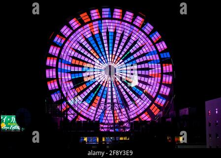 Sapporo Ferris Wheel, farbenfrohe Neonlichter, die nachts beleuchtet werden. Kirmes-Rad auf der Oberseite oder ein Wolkenkratzer. Hokkaido, Japan. Stockfoto