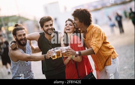 Eine Gruppe glücklicher Freunde, die aushangelt sind und Getränke genießen, Festival Stockfoto