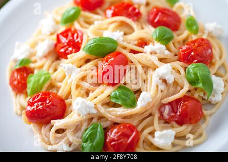 Spaghetti mit Kirschtomaten und frischem Ricotta auf einem Teller. Stockfoto