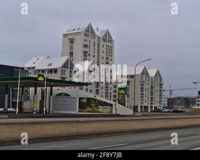 Blick auf die Tankstelle Olís, die von der Firma Iceland Oil Ltd betrieben wird, an der Küstenstraße Sæbraut in der Innenstadt von Reykjavik mit einem Apartmenthaus im Hintergrund. Stockfoto