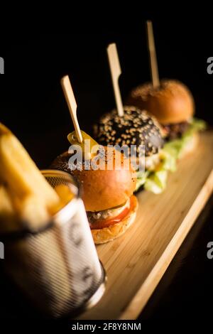 Nahaufnahme von drei Mini-Burgern und Pommes. Stockfoto