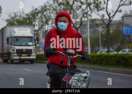Ein Radfahrer sah, wie er eine Gesichtsmask trug, als er durch Staub und Wind fuhr. In Peking treten Staub, Sturm und Niederschläge gleichzeitig auf. Staub vermischt mit Regen, zu den Fußgängern und Fahrzeugen im Freien verursachte eine Menge Ärger. Stockfoto