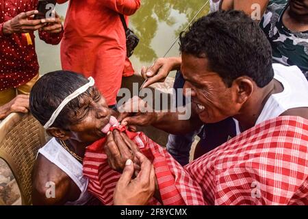 Hooghly, Indien. April 2021. (Die Redaktion bemerkt, dass das Bild Grafiken enthält) EIN Anhänger wird während des Festivals von einem Spießrutenstab in seine Zunge gestochen. Gajan ist ein hinduistisches Fest, das vor allem in Westbengalen sowie im südlichen Teil von Bangladesch gefeiert wird. Das Festival ist mit Hingabe an lord Shiva verbunden, und es geht über eine Woche im letzten Monat des bengalischen Jahres weiter. Völker feiern Gajan, indem sie viele Rituale durchführen, und diejenigen, die diese Rituale durchführen, werden Sannyasi oder Anhänger genannt. Kredit: SOPA Images Limited/Alamy Live Nachrichten Stockfoto